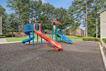 A playground with a red slide and blue slide.